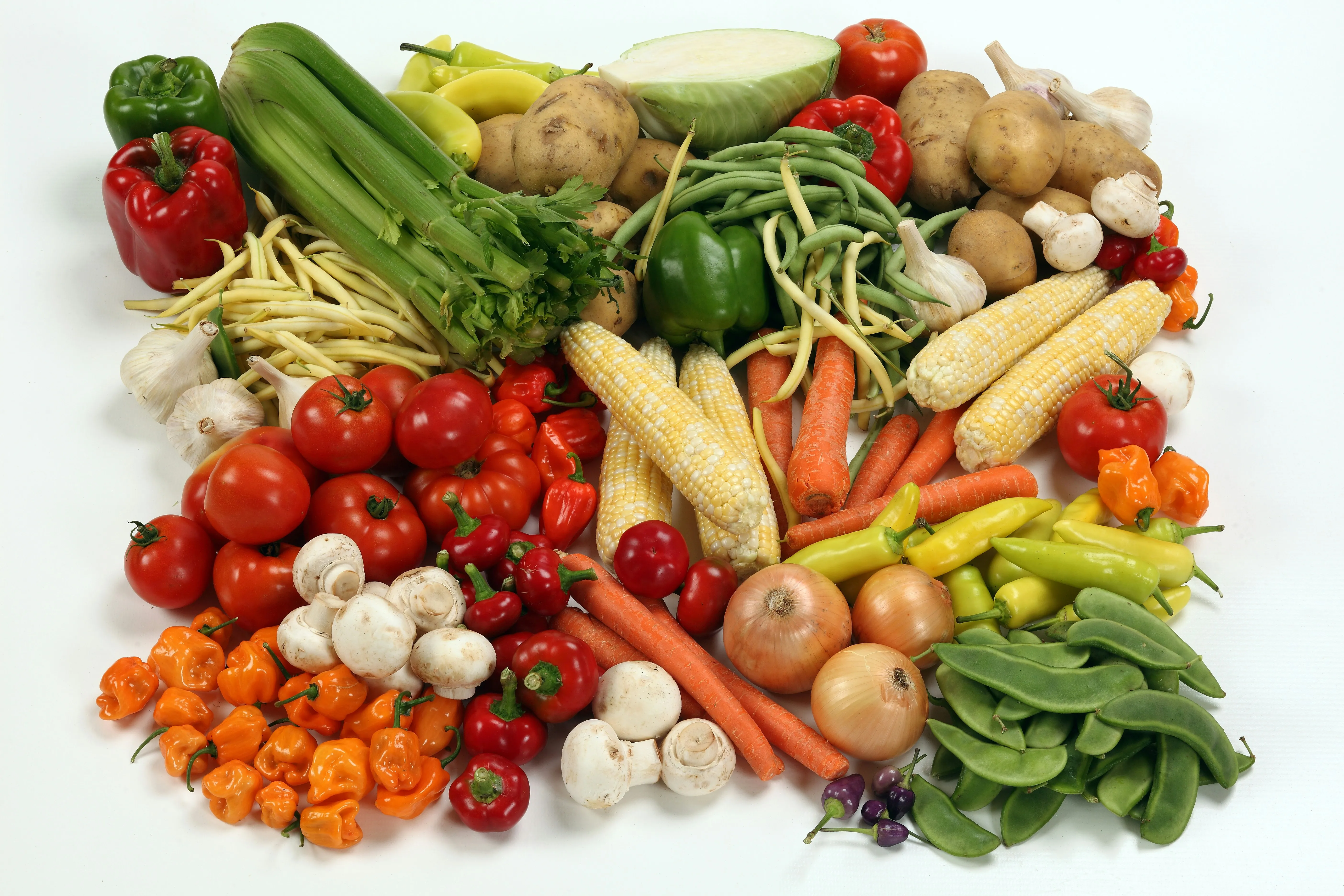 An overhead view of a laid table with flatbread, fresh vegetables, packaged cake and snacks.